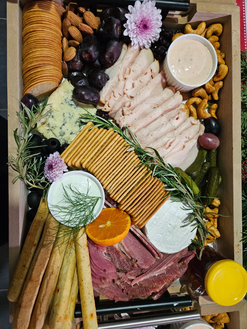 A generous cheese and charcuterie sharing platter with crackers, meats, fruit, nuts, and dips