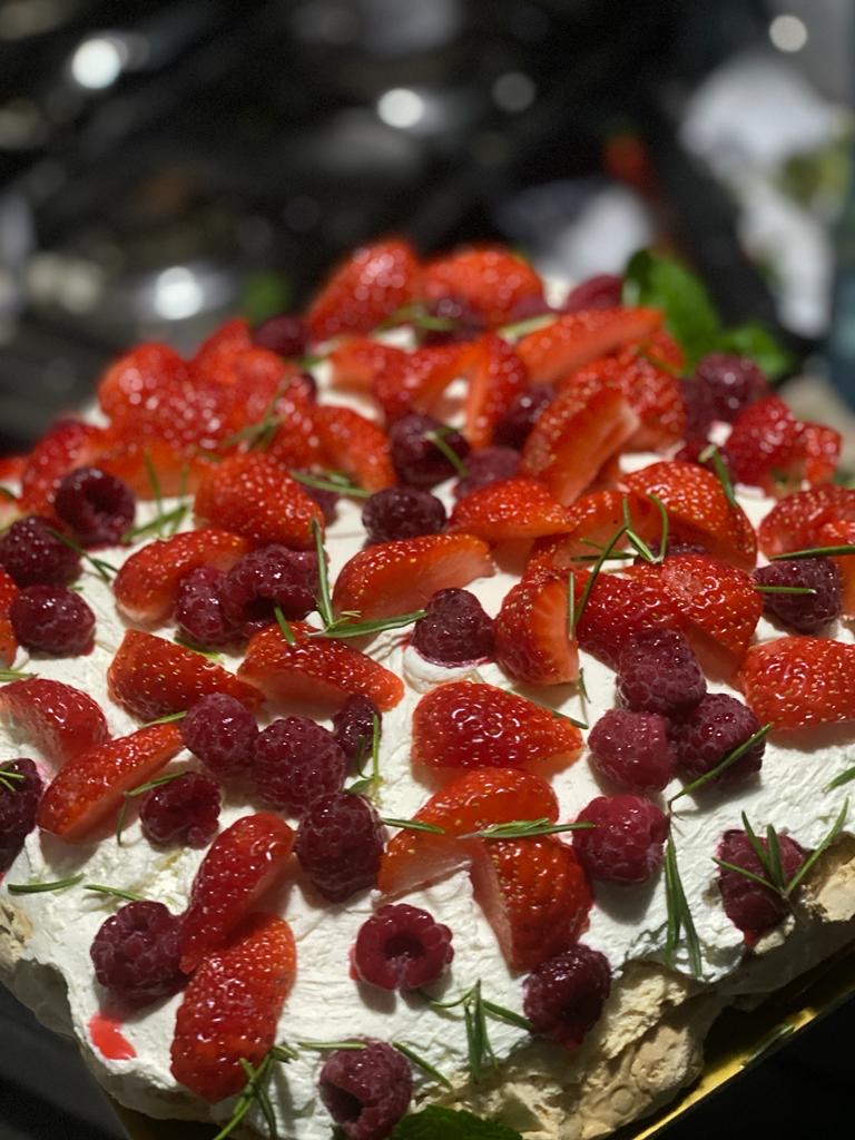 Celebration cake topped with strawberries, raspberries, and rosemary