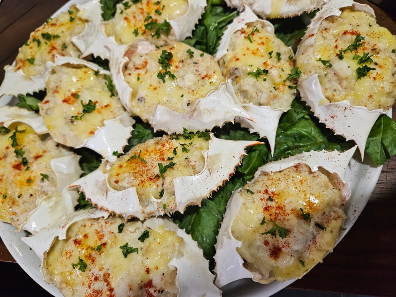 Cheesy baked crab shells presented on fresh greens