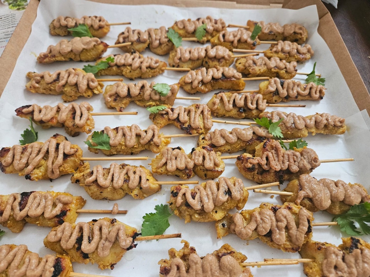 Chicken satay skewers finished with peanut sauce and fresh herbs