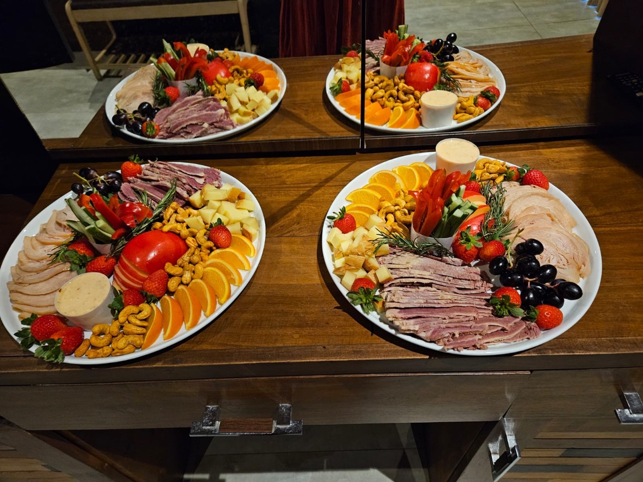 Generous sharing platters arranged with meats, cheese, fruit, nuts, and vegetables