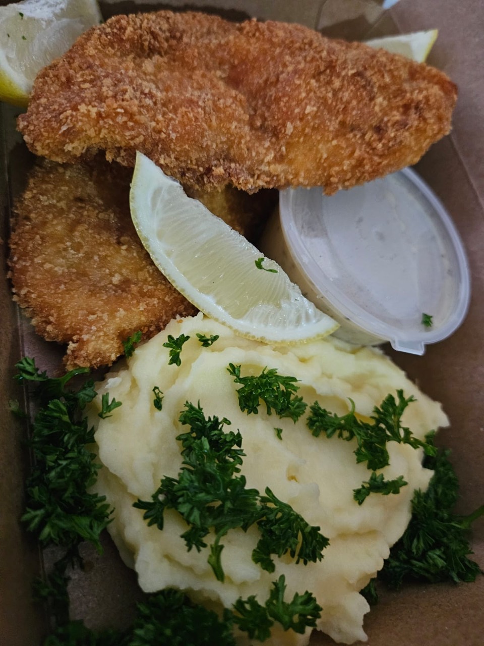 Crispy crumbed chicken with creamy mash, lemon, herbs, and dipping sauce